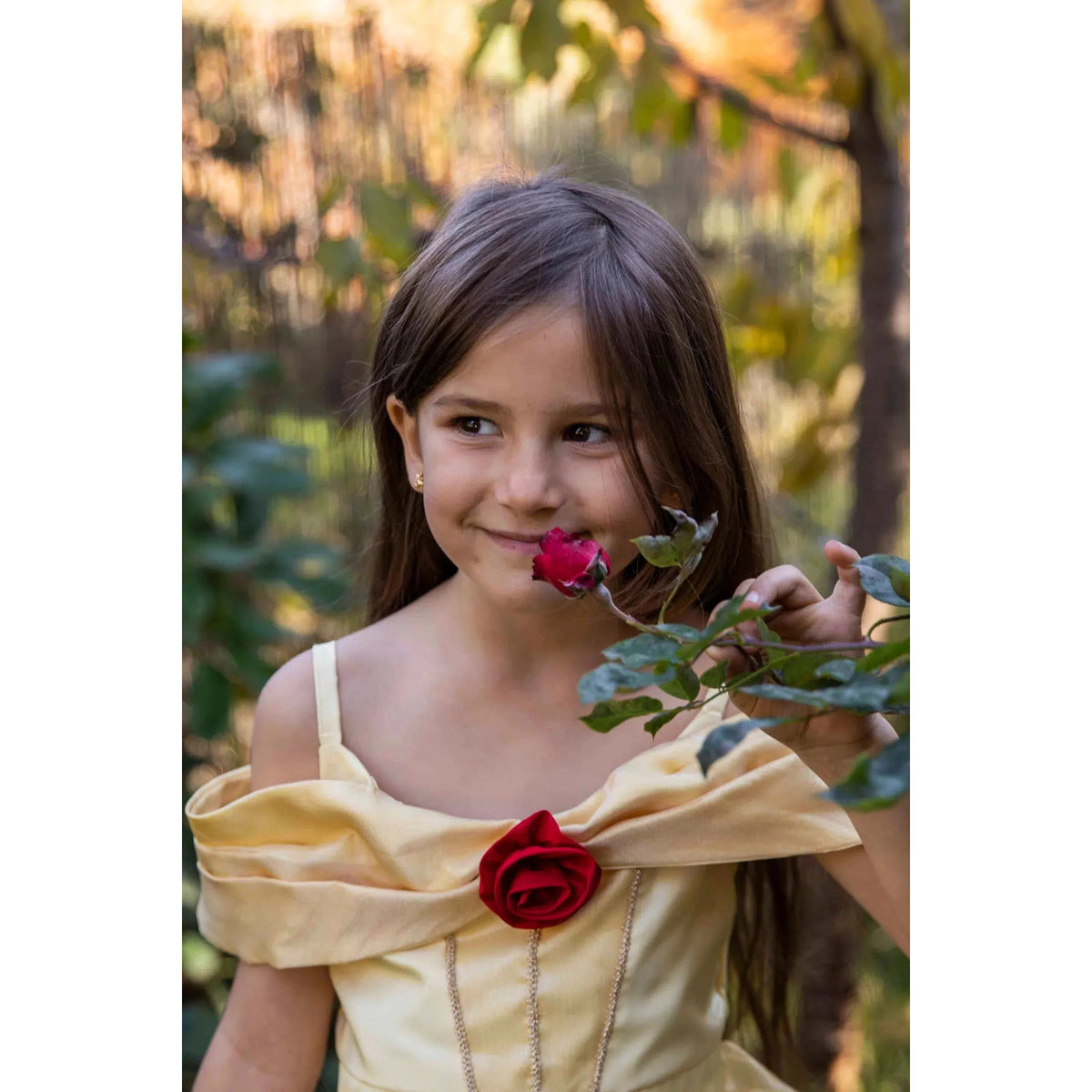Front view of a girl in Boutique Belle Gown smelling a rose.