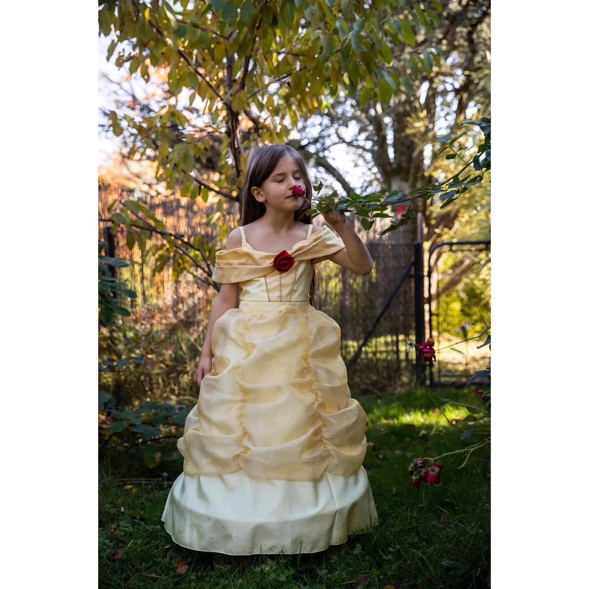 Front full length view of a girl smelling a rose wearing a Boutique Belle Gown.