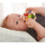 Front view of a baby laying on their back with both hands holding the Clutching Toy Color Carousel in their mouth.
