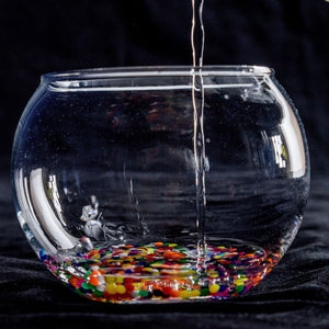 Front view of a bowl of water marbles, with water being poured on top of the marbles.