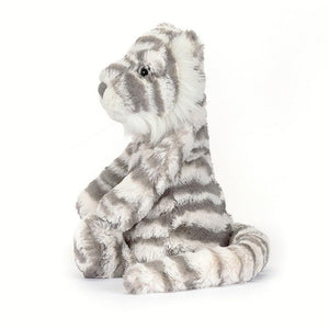 Front left side view of bashful snow tiger sitting against a white background.