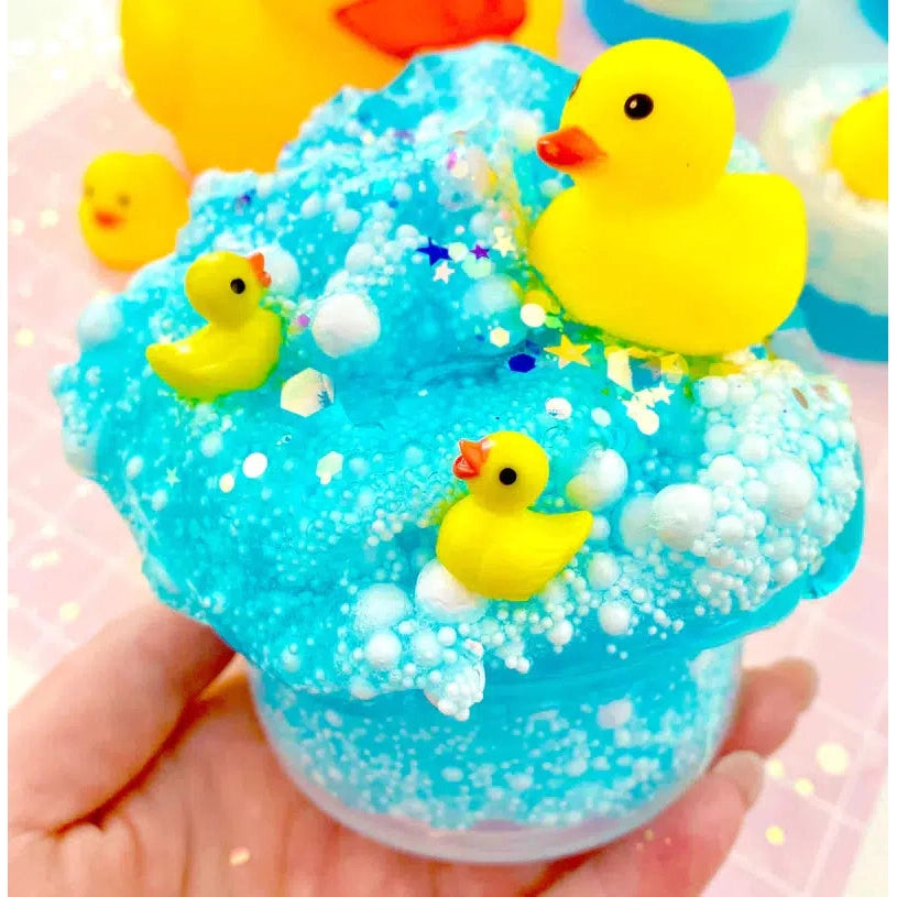 Front view of a person holding Squeaky Clean Bubble Bath Floam Slime in their hand that has been decorated with beads and ducks.