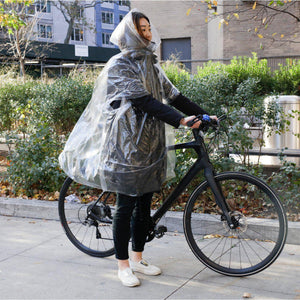Front view of a woman on standing beside her bike with the Rain Poncho-Cyclist.