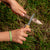 Top view of a set of children's hands using the huckleberry pocketknife to sharpen a stick.
