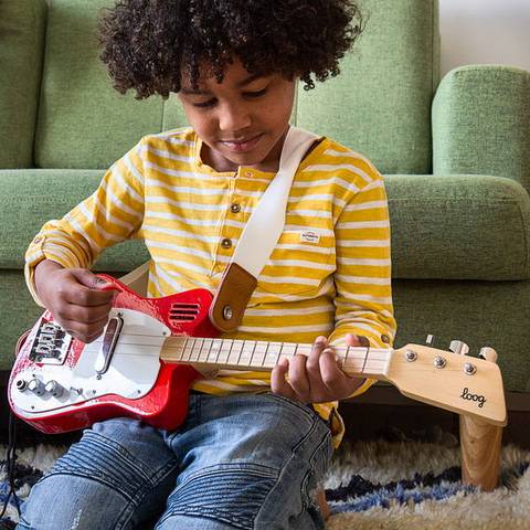 Front view of a child playing the mini red guitar.