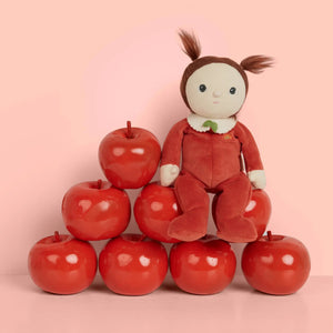 Front view of the Annie Apple Doll sitting on a stack of apples.