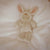 Front view of the Bunny Moppet Doll laying on a soft white blanket.