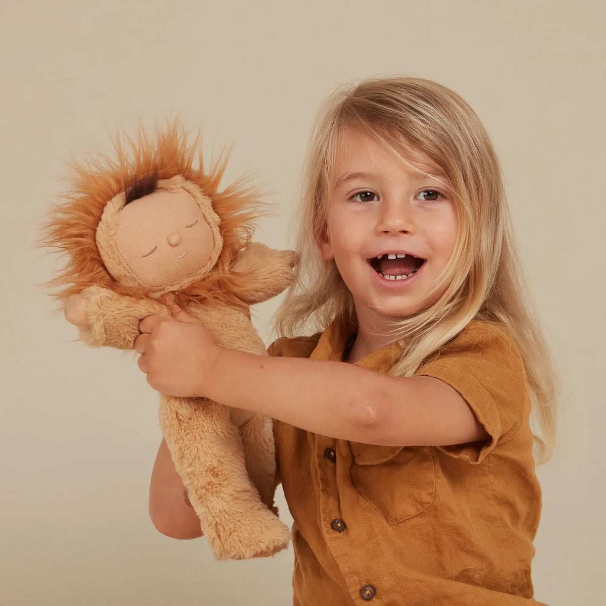 Front view of a young child holding up the Lion Pip Doll.