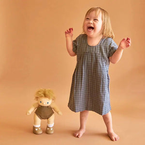 Front view of a little girl standing besides the Poppet Doll who is also standing.