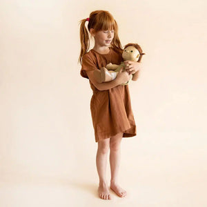 Front view of a young girl standing holding the Pumpkin Doll in her arms.