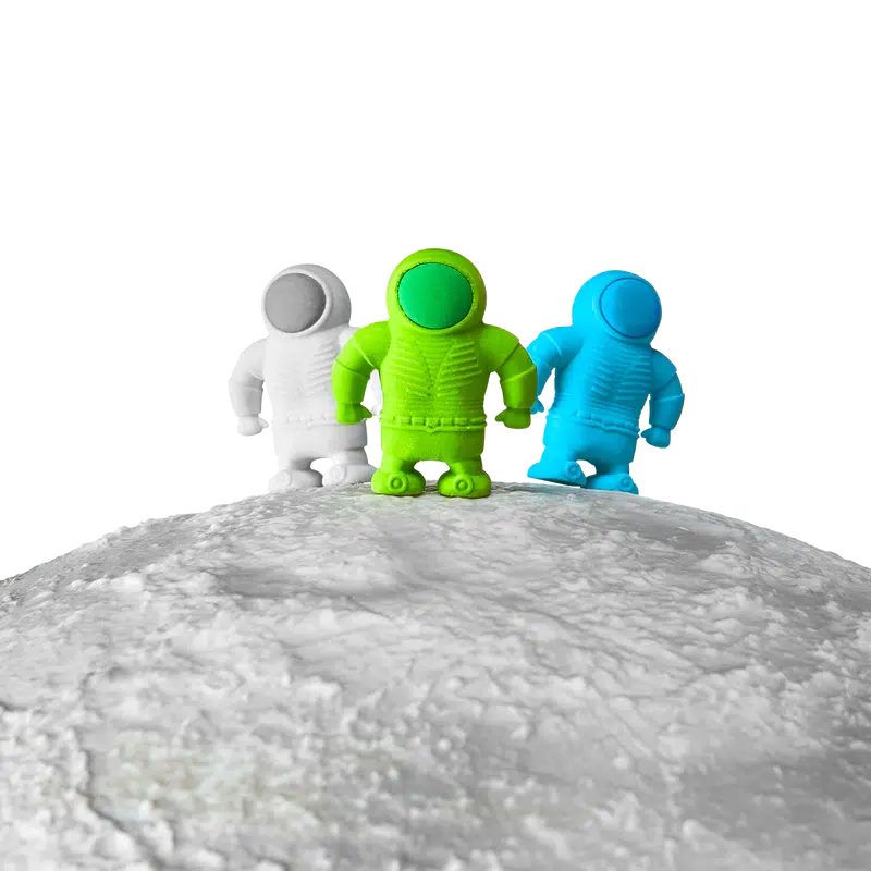 Front view of white, green, and blue astronaut erasers standing on what appears to be the moon.