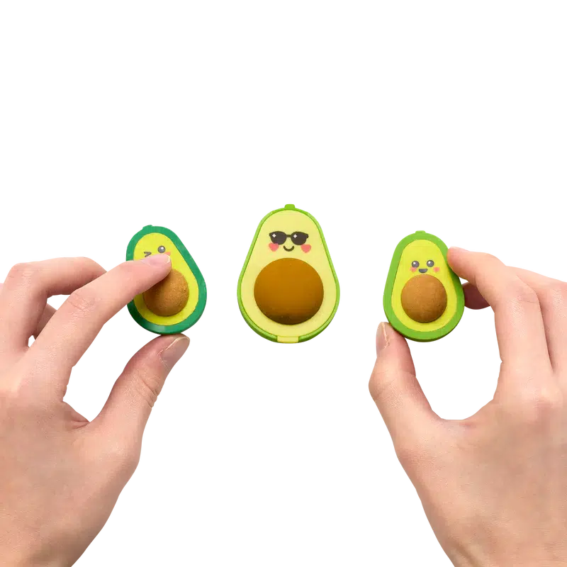 Front view of two hands touching the avocado erasers laying flat with the avocado love sharpener in the middle.