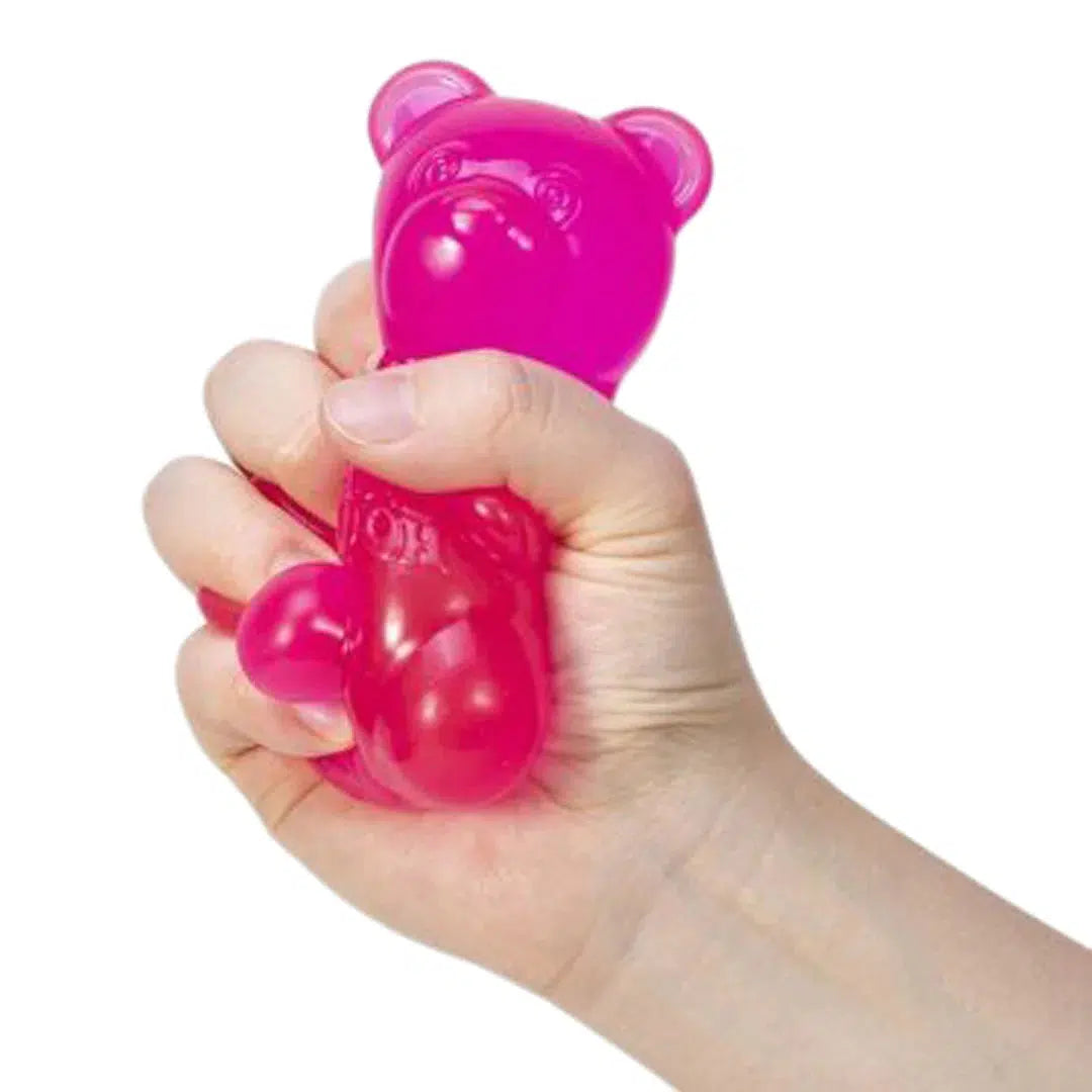 Front view of a person's hand holding and squeezing the pink Nee Doh Gummy Bear.