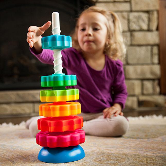 Young child playing with stacked toy (discs ordered big to small)