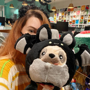 Front view of a woman holding the Undercover Pug in Bat in front of her face.