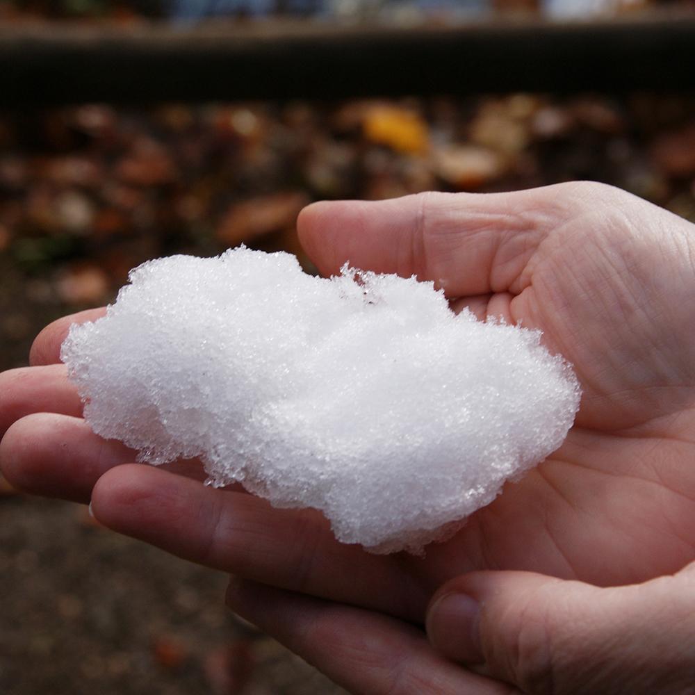 Front view of a persons hands full of polymer snow.