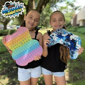 Front view of two girls holding OMG pop fidgety rainbow jumbo gummy bear and tie dye jumbo game congtroller