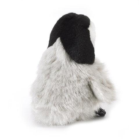 Cute baby penguin finger puppet sitting in an adult's palm