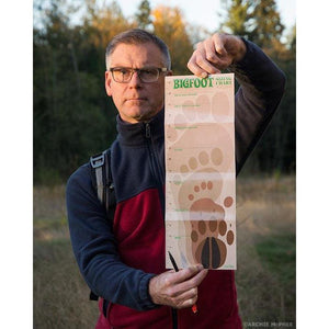 Front view of a man holding up the Bigfoot Research  Kit foot chart.