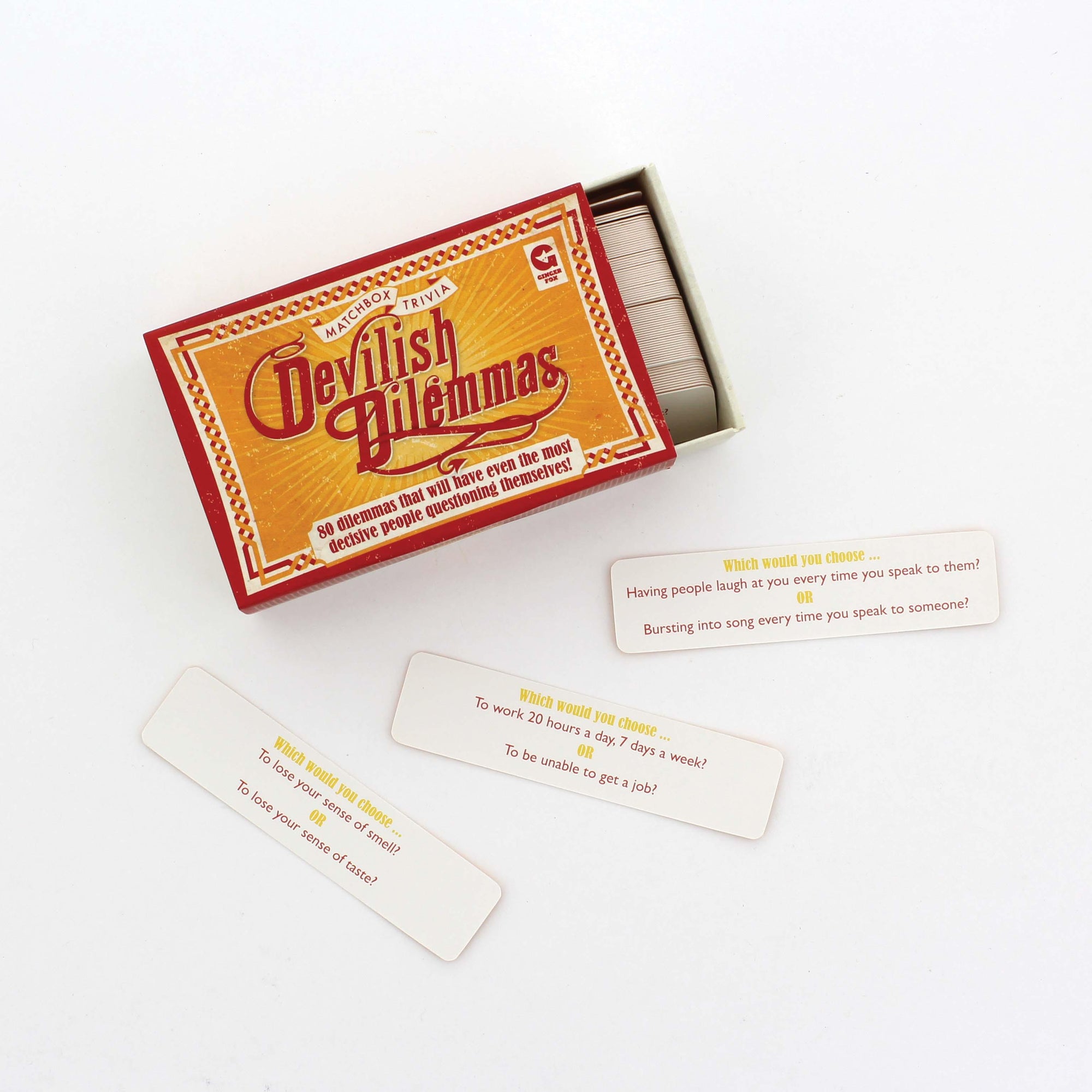 Front view of Devilish Dilemmas game box slightly open and game cards laying out in front of box.