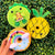 3 plushies (dinosaur, pineapple, and rainbow donut) against green leaf background