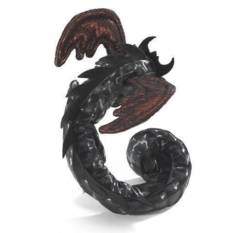 Expressive little black dragon with wings perched on an adult's hand