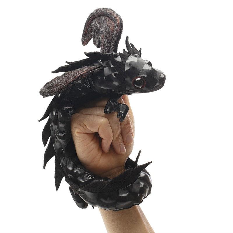 Expressive little black dragon with wings perched on an adult's hand