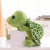 Side view of green turtle plush resting on box