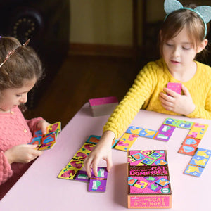 Front view of two young girls sitting at a table playing Giant Shiny Cat Dominoes with the box in the picture.