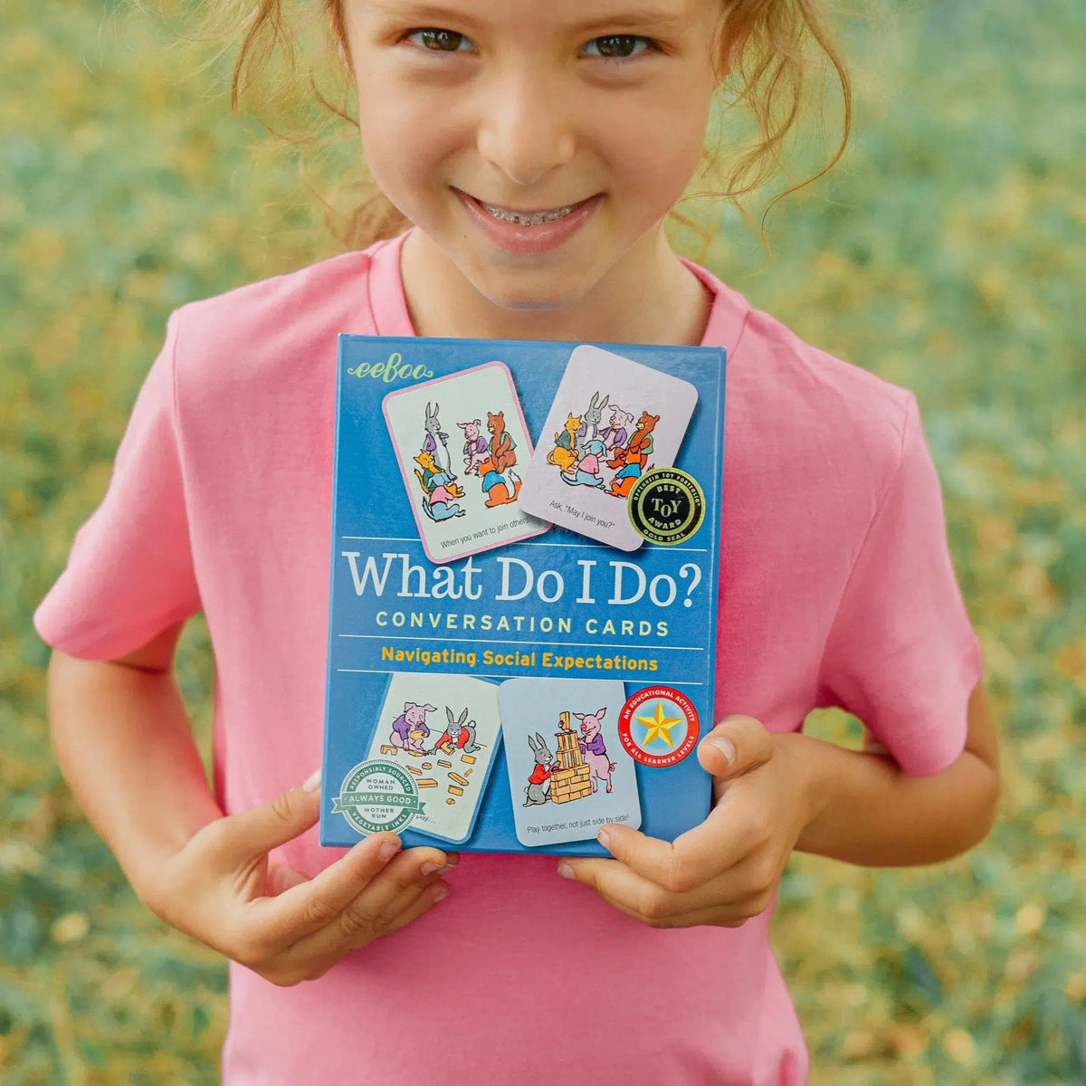 Front view of a young girl holding a box of the What Do I Do? Conversation Cards.