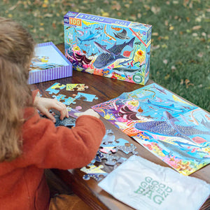 Back view of a child using the poster included in the sharks puzzle to aide in completion of the puzzle.