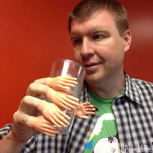Front view of a man with lighter skin tone holding a glass with Finger Hands on each finger.
