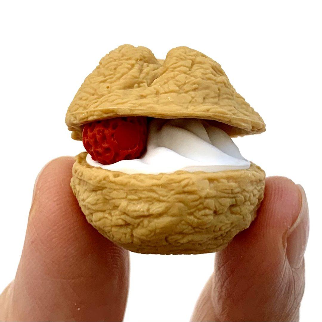 Front view of a cream puff with white cream and a strawberry inside.