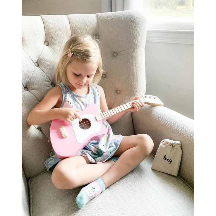 Front view of a child playing the mini pink guitar.