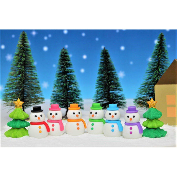 Front view of all the colors of the Puzzle Eraser-Snowman including red, pink, orange, green, blue, and purple against a Christmas background with two Christmas trees.