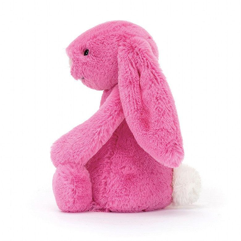 Side view of bashful hot pink bunny sitting.
