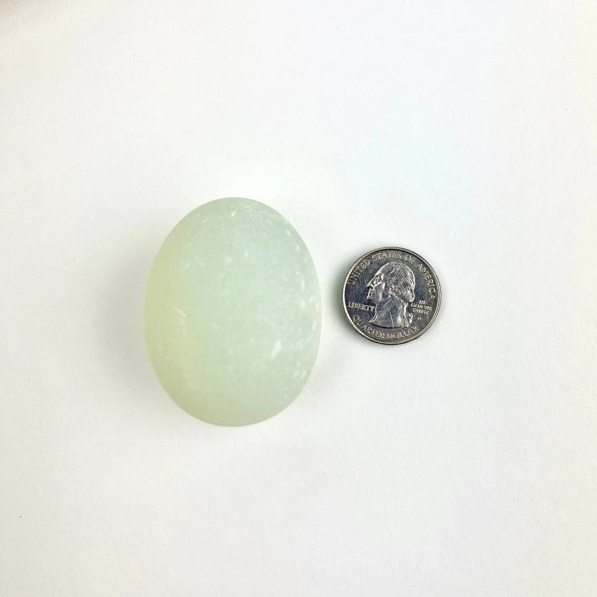 Top view of a magic egg next to a quarter, showing size comparison.