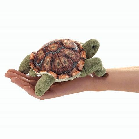 Green tortoise finger puppet, with a colorful shell, in an adults palm.